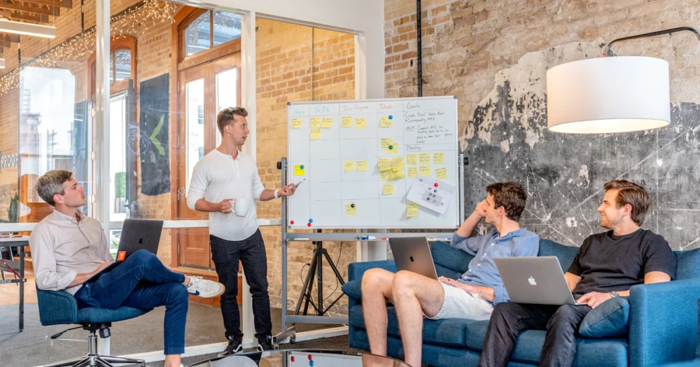 Deltagare diskuterar underlag vid ett möte med datorer och whiteboard